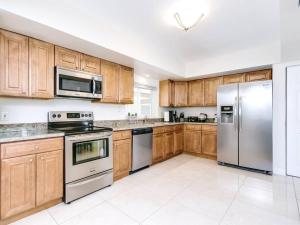 a kitchen with wooden cabinets and stainless steel appliances at Modern Spacious 5-Bedroom Home with Pool in Hollywood