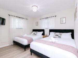 two beds in a bedroom with white walls at Modern Spacious 5-Bedroom Home with Pool in Hollywood +18 photos