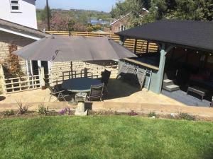 eine Terrasse mit einem Sonnenschirm, einem Tisch und Stühlen in der Unterkunft Bens Hollow with hot tub in Bredon