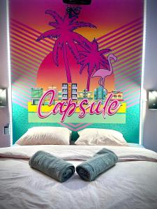 a bed with two pillows and a sign with palm trees at Capsule Miami Vice - Jacuzzi - Billard - Ecran cinéma & Netflix - Ping-Pong - Nintendo & Jeux- in Liévin