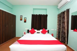 a bedroom with a large white bed with red pillows at Flagship The Maple Tree Hotels in Bhubaneshwar