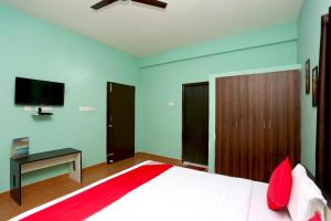 a bedroom with a bed with red pillows and a tv at Flagship The Maple Tree Hotels in Bhubaneshwar