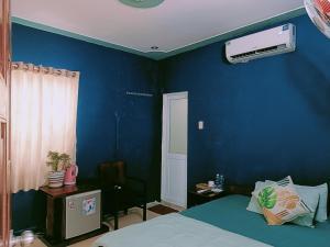 1 dormitorio con una pared azul, 1 cama y aire acondicionado en Nhà nghỉ Phương Dung en Phu Quoc