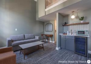 a living room with a couch and a kitchen at Prentiss House by Thatch in Cambridge