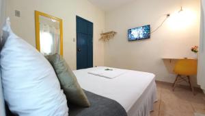 a bedroom with a white bed and a yellow chair at Quarto em Hospedaria no Centro Histórico in Ouro Preto