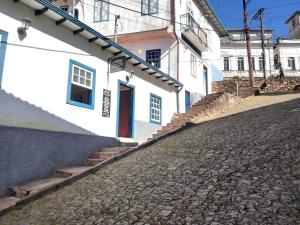 una calle adoquinada junto a un edificio blanco en Quarto em Hospedaria no Centro Histórico, en Ouro Preto