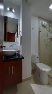 y baño con aseo, lavabo y espejo. en Apartasuites AAA Modelia Bogotá, en Bogotá