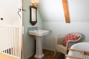 a bathroom with a sink and a mirror and a chair at Skylarks, enjoy the decking overlooking your garden and wildflower meadow in Old Newton