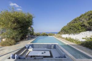 einen Infinity-Pool mit einem Sofa und einem Tisch in der Unterkunft Villa Alkyoni · Beautiful 8-person Family Villa with Great Views in Naoussa
