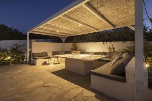 eine Terrasse mit einem Tisch und Sofas unter einer Pergola in der Unterkunft Villa Alkyoni · Beautiful 8-person Family Villa with Great Views in Naoussa