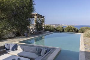 einen Pool mit Sofa und Stühlen daneben in der Unterkunft Villa Alkyoni · Beautiful 8-person Family Villa with Great Views in Naoussa