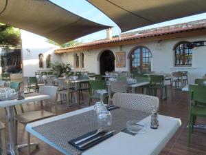 Les Villas de la Résidence U Veniqui في فافون: مطعم بطاولات بيضاء وكراسي خضراء