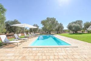 ein Swimmingpool mit Stühlen und einem Sonnenschirm in der Unterkunft New Trulli Eden 101 with private pool and jacuzzi in San Michele Salentino