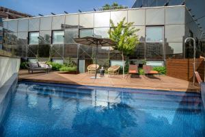 - une piscine avec des chaises et un parasol à côté d'un bâtiment dans l'établissement Ocean Drive Barcelona, à Barcelone