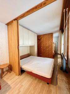 sypialnia z łóżkiem i drewnianą szafką w obiekcie Monolocale Rainalter 1D w Madonna di Campiglio
