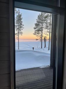 d'une porte coulissante en verre offrant une vue sur une cour enneigée. dans l'établissement Villa Vilmala, à Sääskilahti