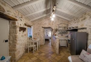 una cucina con pareti in pietra, tavolo e frigorifero di Marathia Cottages Zakynthos Greece a Marathias
