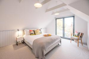 a white bedroom with a bed and a window at Chapel House in Woodbridge