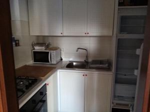 a kitchen with white cabinets and a sink and a microwave at Casa Luca in Tremosine Sul Garda