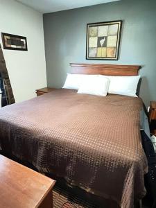1 dormitorio con 1 cama con edredón marrón en Eastside Suites, en Lynchburg