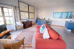 a living room with a red couch and a kitchen at 139 Longships - Self Catering Flatlet in Plettenberg Bay