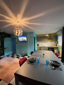 a kitchen with a table and a dining room at Capsule Miami Vice - Jacuzzi - Billard - Ecran cinéma & Netflix - Ping-Pong - Nintendo & Jeux- in Liévin