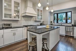 a kitchen with white cabinets and a island with stools at Grand Long Branch Home 1 Block to Beach! in Long Branch +32 photos