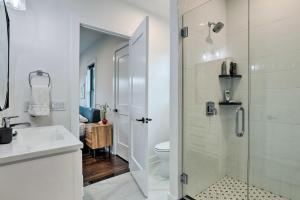 a white bathroom with a shower and a toilet at Grand Long Branch Home 1 Block to Beach! in Long Branch