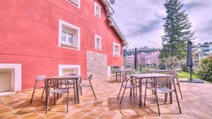 a patio with tables and chairs next to a red building at PURA VIDA PIRINEOS in Jaca