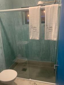 a bathroom with a shower with a toilet and towels at A casa di Maria in Ubatuba