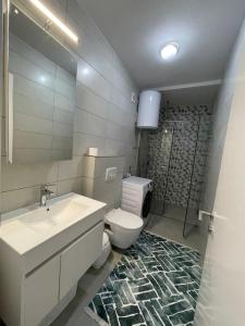 a bathroom with a sink and a toilet and a mirror at Lovely apartment in Peja Citycenter in Peje +8 photos