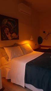 a bedroom with a white bed with a painting on the wall at A casa di Maria in Ubatuba