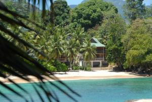 a house on a beach with palm trees at LÌlot Beach Chalets in Glacis