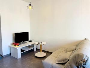 a living room with a couch and a desk with a television at L'Esplanade in Besançon