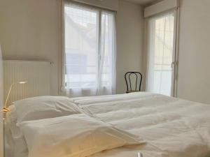 ein großes weißes Bett in einem weißen Zimmer mit Fenstern in der Unterkunft Majestic in Besançon