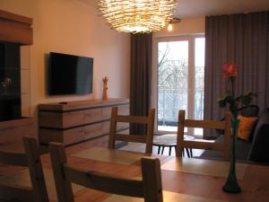 uma sala de estar com uma mesa e cadeiras e uma televisão em 4You Apartament em Białystok