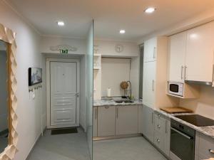 une cuisine avec des placards blancs et une porte donnant sur un comptoir dans l'établissement Casa Amarela AL 3030, à Horta