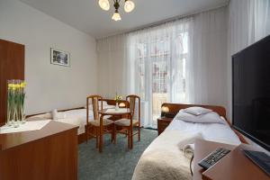 a bedroom with a bed and a desk and a table at Stella in Krynica Zdrój