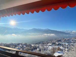 een raam met uitzicht op een met sneeuw bedekte stad bij Moderno appartamento con splendida vista Alpi in Crans-Montana
