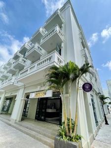 a large white building with palm trees in front of it at Myrtle Boutique Hotel Phu Quoc in Phu Quoc