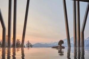 a woman sitting in the water in a infinity pool at Hotel Olangerhof in Valdaora