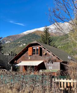 a large wooden house with a mountain in the background at Chalet à proximité de l'Ubaye in Jausiers