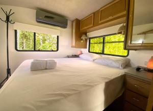 聖特雷莎海灘的住宿－Hummingbird Garden community Yoga & Wellness space，卧室配有一张白色大床和两个窗户