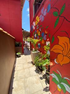 ein rotes Gebäude mit seitlich bemalten Blumen in der Unterkunft Pousada Arco Iris in Gonçalves