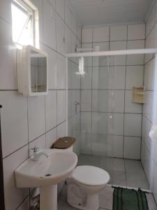 a white bathroom with a toilet and a sink at Trindade Hospeda - Estúdios e Casa Vila Trindade in Trindade