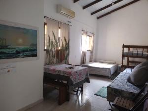 a living room with a table and a bed at Trindade Hospeda - Stúdios e Suítes privativos Vila Trindade in Trindade