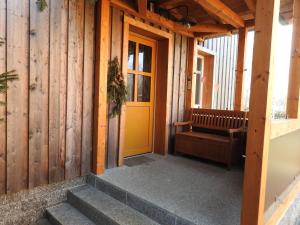eine gelbe Tür in einem Holzgebäude mit einer Treppe in der Unterkunft Ferienhof Olbasee in Kleinsaubernitz