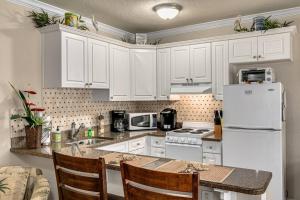 a kitchen with white cabinets and a white refrigerator at Walk to the Beach and Restaurants! - Coconut Villa's Suite 2 in St Pete Beach