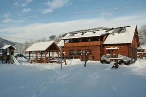 ein Blockhaus mit Schnee auf dem Boden vor dem Haus in der Unterkunft Penzion Rzehaczek in Dolní Lomná