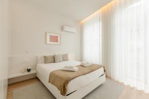 - une chambre blanche avec un lit et des serviettes dans l'établissement Boavista Collection Apartment - Minho's Guest, à Braga